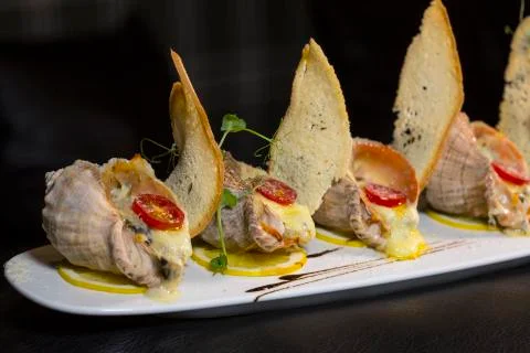 Rape baked with cheese, cherry tomato. Shellfish baked in shell. Rapane. Stock-Fotos