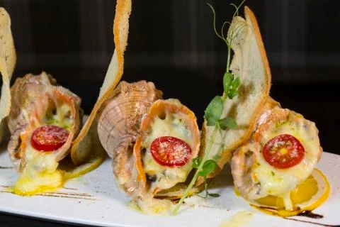 Rape baked with cheese, cherry tomato. Shellfish baked in shell. Rapane. Stock Photos