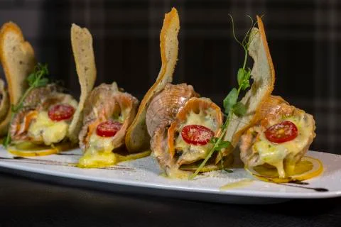 Rape baked with cheese, cherry tomato. Shellfish baked in shell. Rapane. Stock Photos