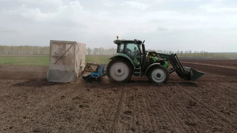 Rapeseed sowing tractor seeder selection field spring. In the background, wheat Stock Footage 129816910