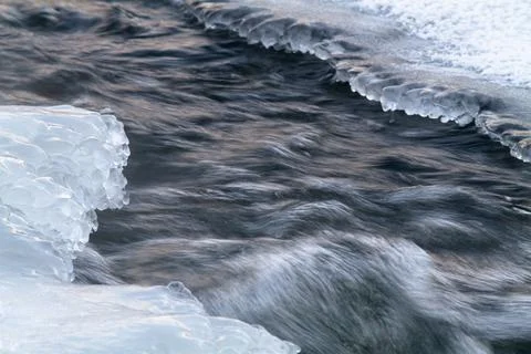 The rapid flow of the river between the icy shores Stock Photos