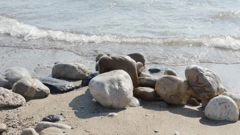 The rapid, rhythmic flow of gentle waves washing over a cluster of smooth, s Stock-Footage 318798580