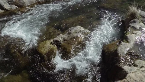 A rapid river flowing downstream is split into two paths by a large boulder in Stock Footage 328659243