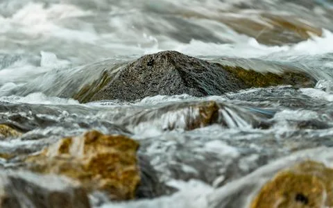 Rapid spring river flowing over rocks forming white water waves, closeup de.. Foto stock
