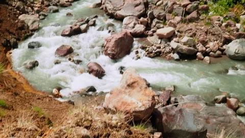 Rapid water flows through rocky riverbed in a sunny landscape with greenery Stock Footage 313107397