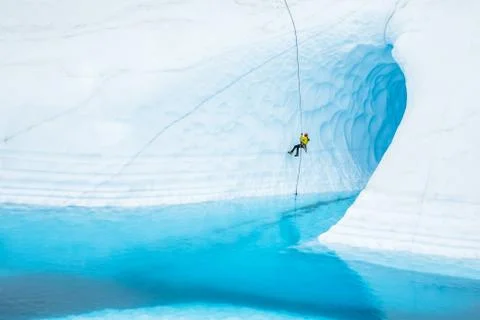 Rappeling in front of a large ice cave flooded with a blue pool on the Matanu Stock Photos