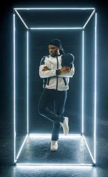 Rapper posing in illuminated cube, dark background Stock Photos