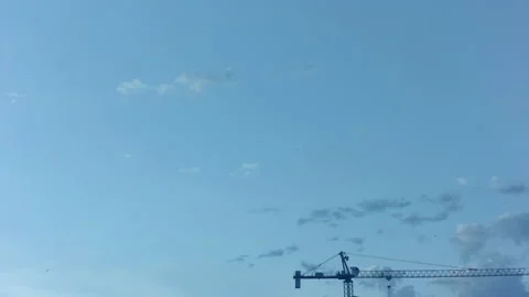 Rare clouds float in the blue sky. In the foreground is a crane. Time laps. Stock Footage 142080324