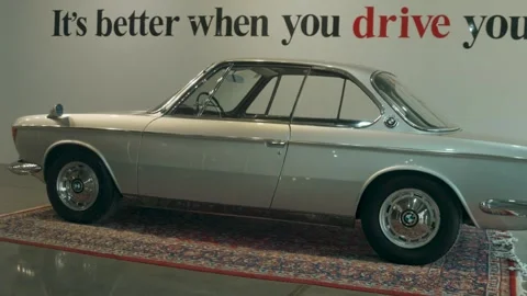 Rare silver BMW e9 coupe, displayed on a Persian carpet in an indoor showroom Stock Footage 308924478