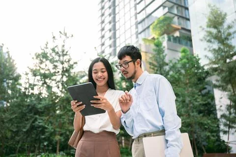 Rare view of young asian professionals collaborating outdoors with a tablet Stock Photos