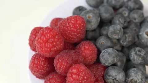 Raspberries and blueberries rotating on light background represent superfood Video stock 332874822