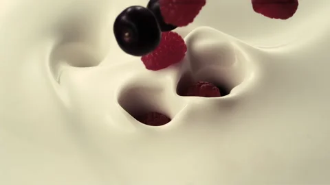 Raspberries and cherries fall down into pouring creamy milk Stock Footage 147511492