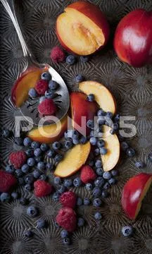 Raspberries, blueberries and sliced red plums Stock Photos