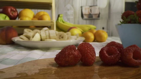 Raspberries on cutting board with other fruit around kitchen - tracking shot Stock Footage 341191265