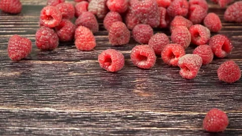Raspberries fall and roll on a dark wooden surface. Stock Footage 207203974