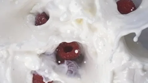 Raspberries falling into milk with splashes in slow motion macro top view Stock Footage 344849006