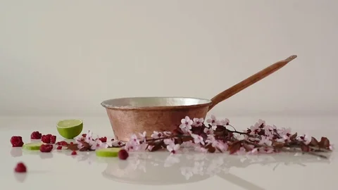 Raspberries falling into a pot of copper decorated with lime and blossom .. Video stock 73743559