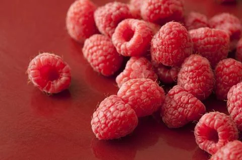 Raspberries on red surface Stock Photos