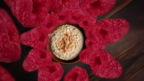 Raspberries spiraling and falling down into an oatmeal bowl slow motion Stock Footage 258483693