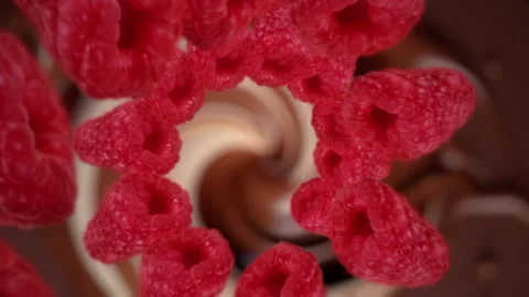 Raspberries spiraling and falling in the liquid milkshake chocolate slow motion Video stock 258512500
