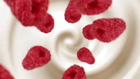 Raspberries spiraling and falling in the liquid milk  slow motion Stock Footage 258513751