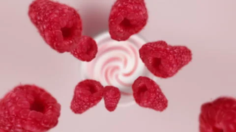 Raspberries spiraling and falling in the yogurt bowl slow motion Stock Footage 258545820