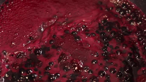 The raspberry and blueberry sauce is bubbling in the pot. Close up. Stock Footage 141930894