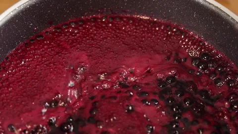 The raspberry and blueberry sauce is bubbling in the pot. Stock Footage 141930963