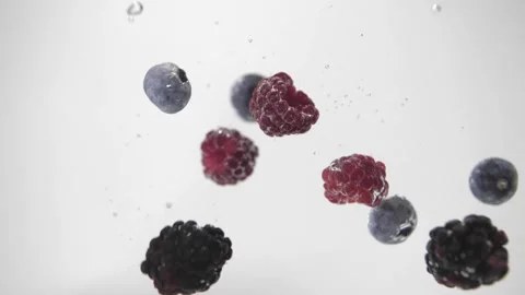 Raspberry, blueberry, raspberries falling in to water on white background Stock Footage 156607284