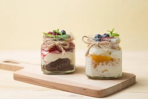 Raspberry cake in glass jar with fresh fruit and cream cheese on wooden backg Stock Photos