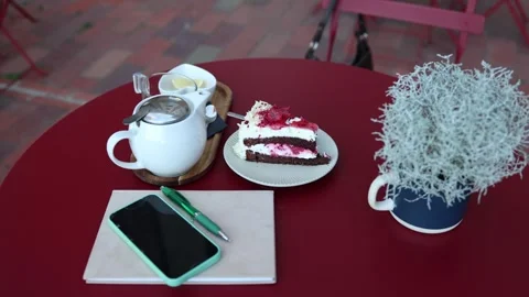 Raspberry cake tea and smartphone on a cozy outdoor cafe table Stock Footage 345028816