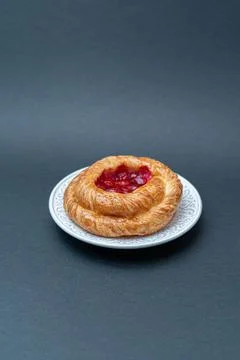 Raspberry cake on a white plate on a black background Stock Photos
