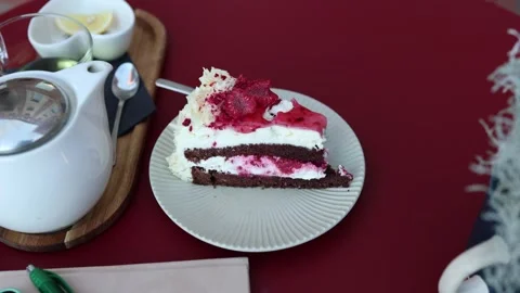 Raspberry chocolate cake with tea and lemon on cafe table Stock Footage 345028841