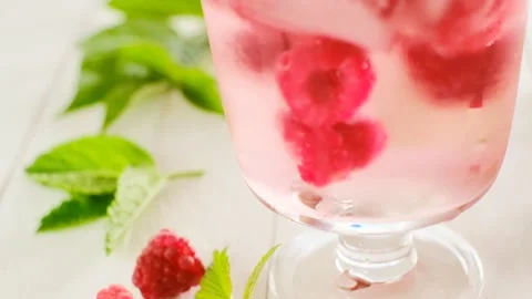 Raspberry cocktail. Ice cubes with raspberries in a glass with mineral water Stock Footage 182514573