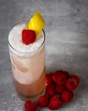 Raspberry cocktail set on top of a stone surface surrounded by raspberries Stock Photos