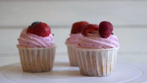 Raspberry cupcakes with fresh berries rotate on a stand on a white background Stock Footage 142964039