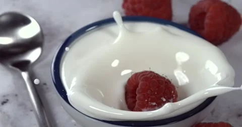 Raspberry falling into a bowl of milk with splash in super slow motion Stock Footage 344848462