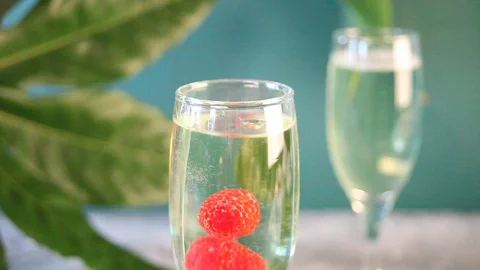 Raspberry falling into a glass of champagne Stock Footage 125355783