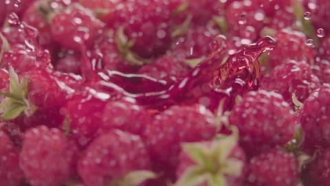 Raspberry falling in juice with splash between raspberries. Slow motion. Stock Footage 92678616