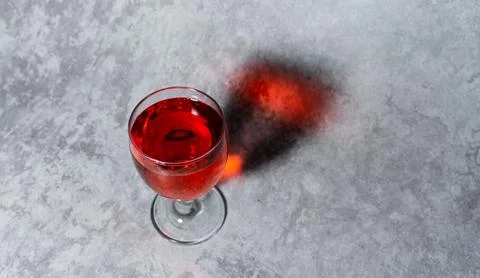 Raspberry flavored red syrup in a glass cup isolated on a gray background Stock Photos