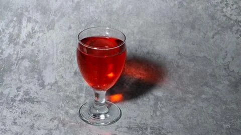 Raspberry flavored red syrup in a glass cup isolated on a gray background Stock Photos