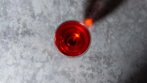 Raspberry flavored red syrup in a glass cup isolated on a gray background Stock Photos