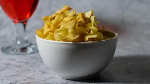 Raspberry flavored red syrup in a glass cup and cassava chips in a white pl.. Stock Photos