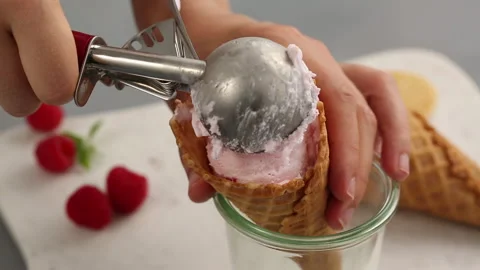 Raspberry ice cream in a waffle cone being scooped Stock Footage 242603511