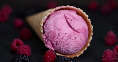 Raspberry ice cream in a waffle cone on a black background, delicious sweet cold Stock Footage 295947111