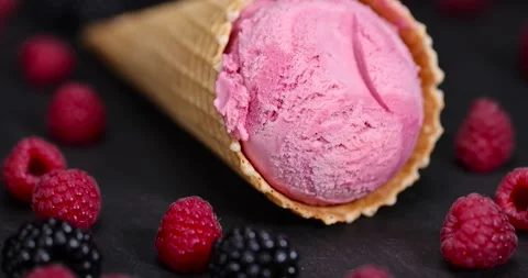 Raspberry ice cream in a waffle cone on a black background, delicious sweet cold Stock Footage 296168680