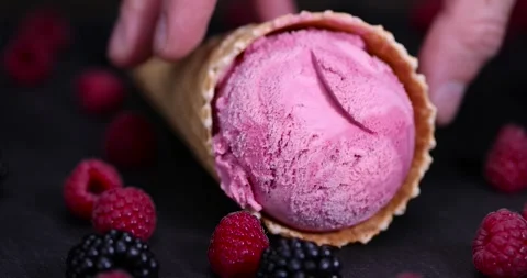Raspberry ice cream in a waffle cone on a black background, delicious sweet cold Stock Footage 296313496