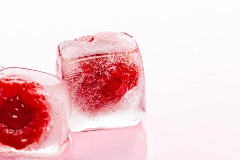Raspberry ice cubes on pink glossy background Stock Photos