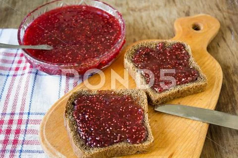 Raspberry jam and a slice of black bread ~ Premium Photo #61649544