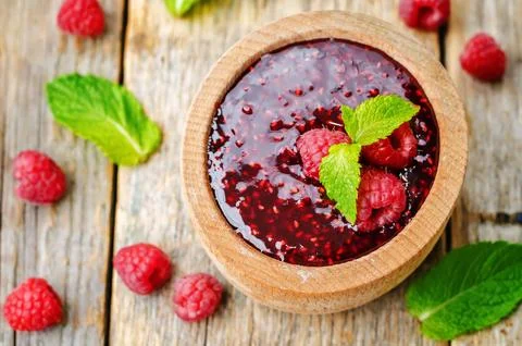 Raspberry jam on a dark wood background. the toning. selective focus Stock Photos